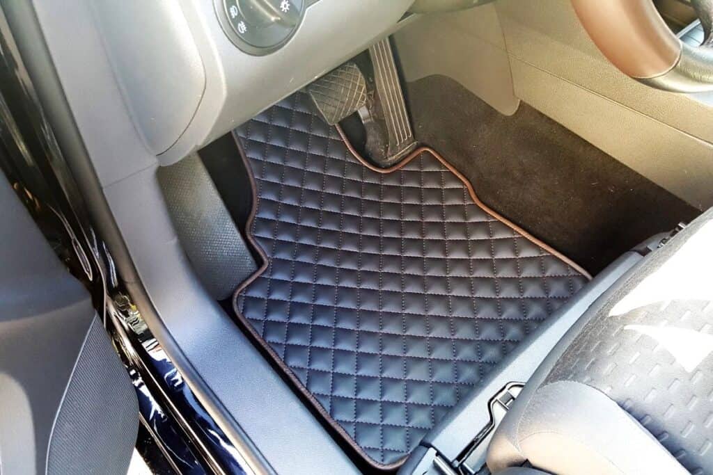 Quilted car floor mat fitted inside a vehicle footwell.