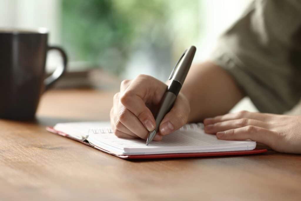 Person writing in a notebook to help organise thoughts and find clarity.