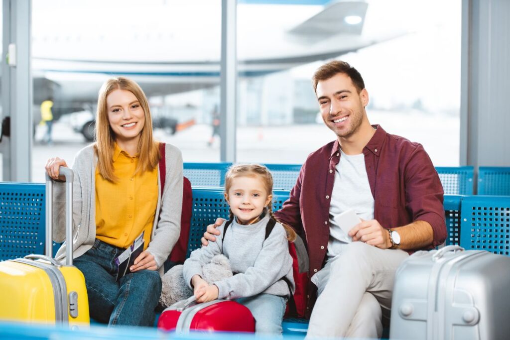 Family sitting at the airport with suitcases before flying abroad.