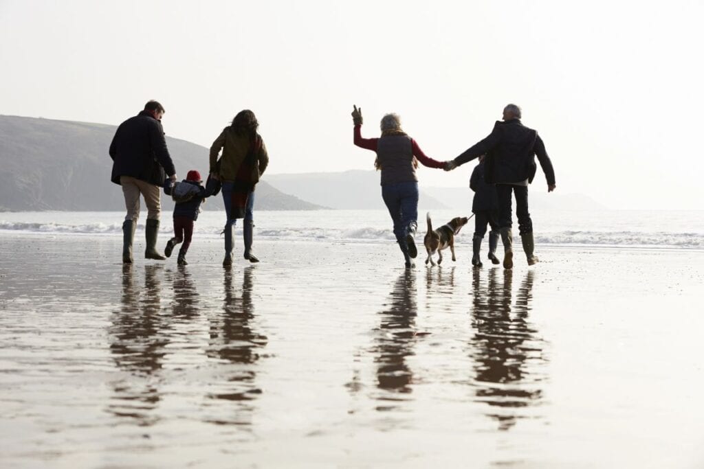 Families walking together along the beach on a multi-family holiday.