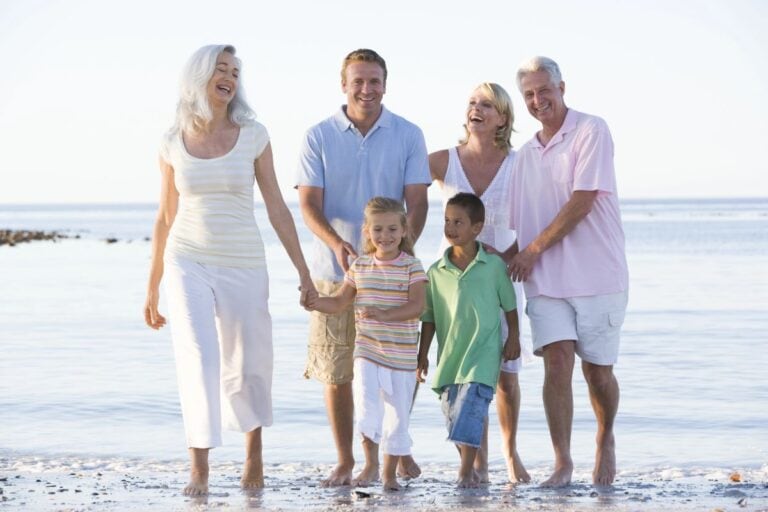 Multi-generational family walking together on a beach holiday.