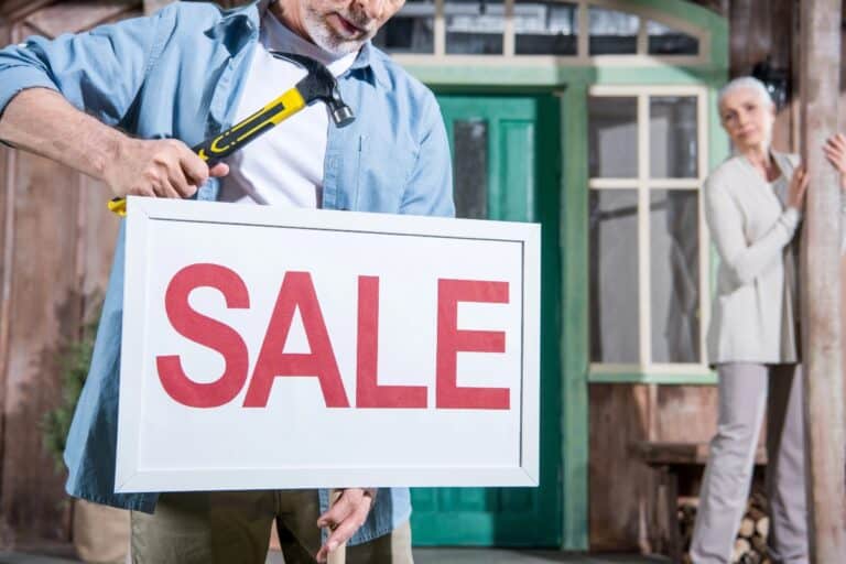 Man putting up a house for sale sign outside a UK home
