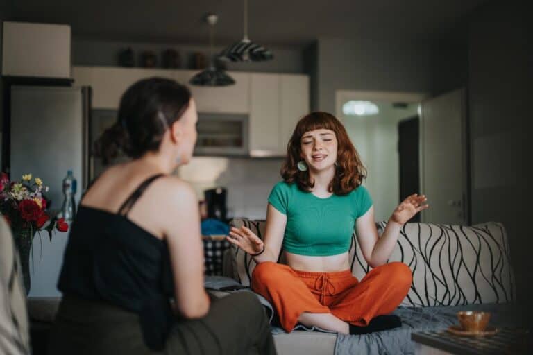 Two women talking at home while one offers support during a difficult conversation.