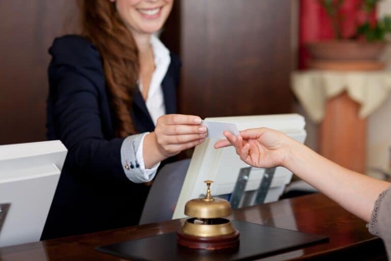 Hotel receptionist handing a keycard to a guest at the front desk