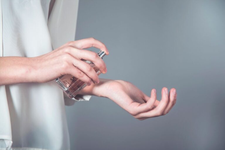 Person spraying perfume onto their wrist while testing a fragrance