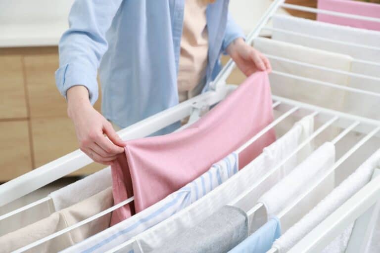 Person hanging clothes on an indoor airer to dry laundry indoors.